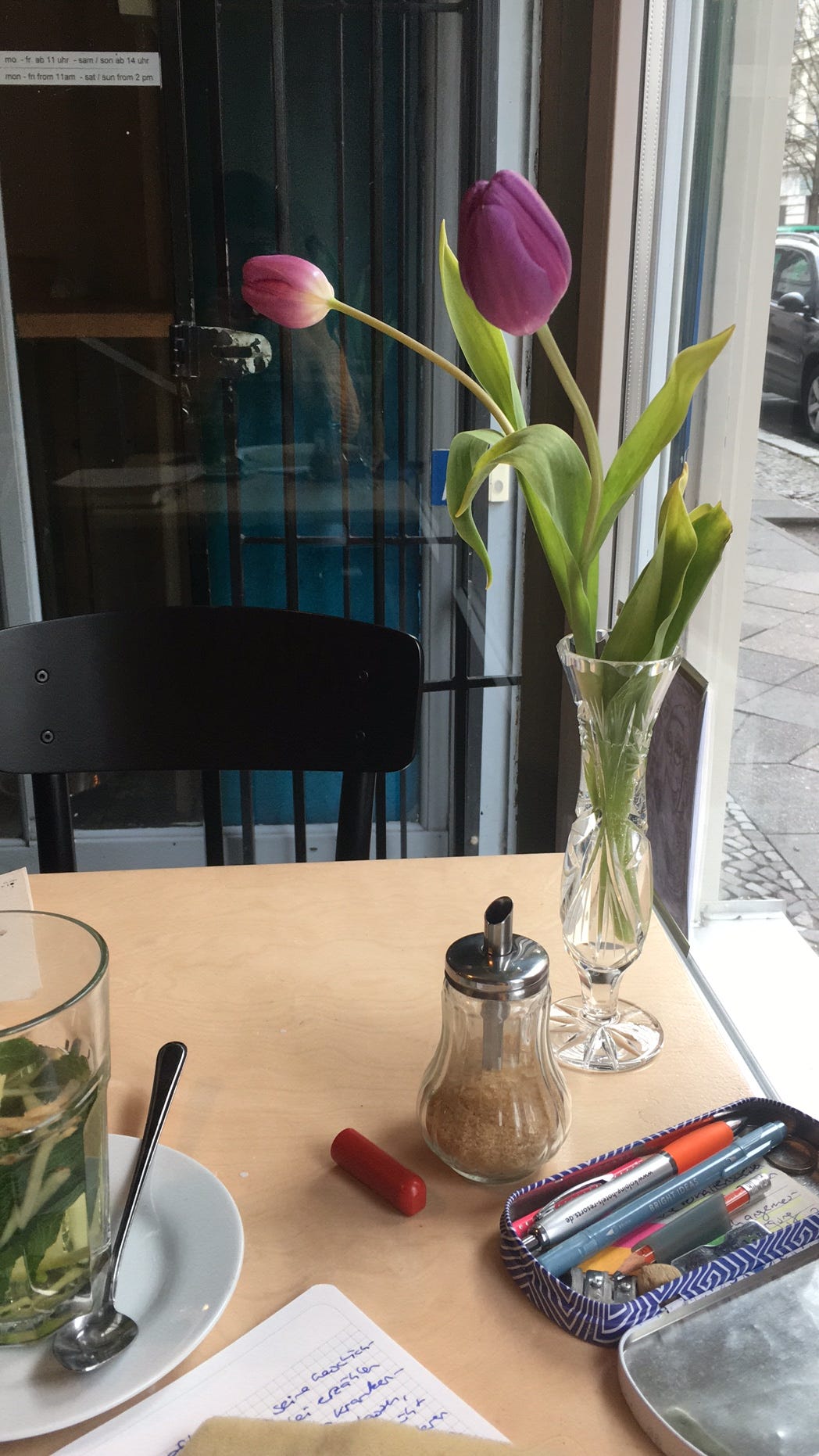 Cafétisch mit Tulpen und Schreibmaterial