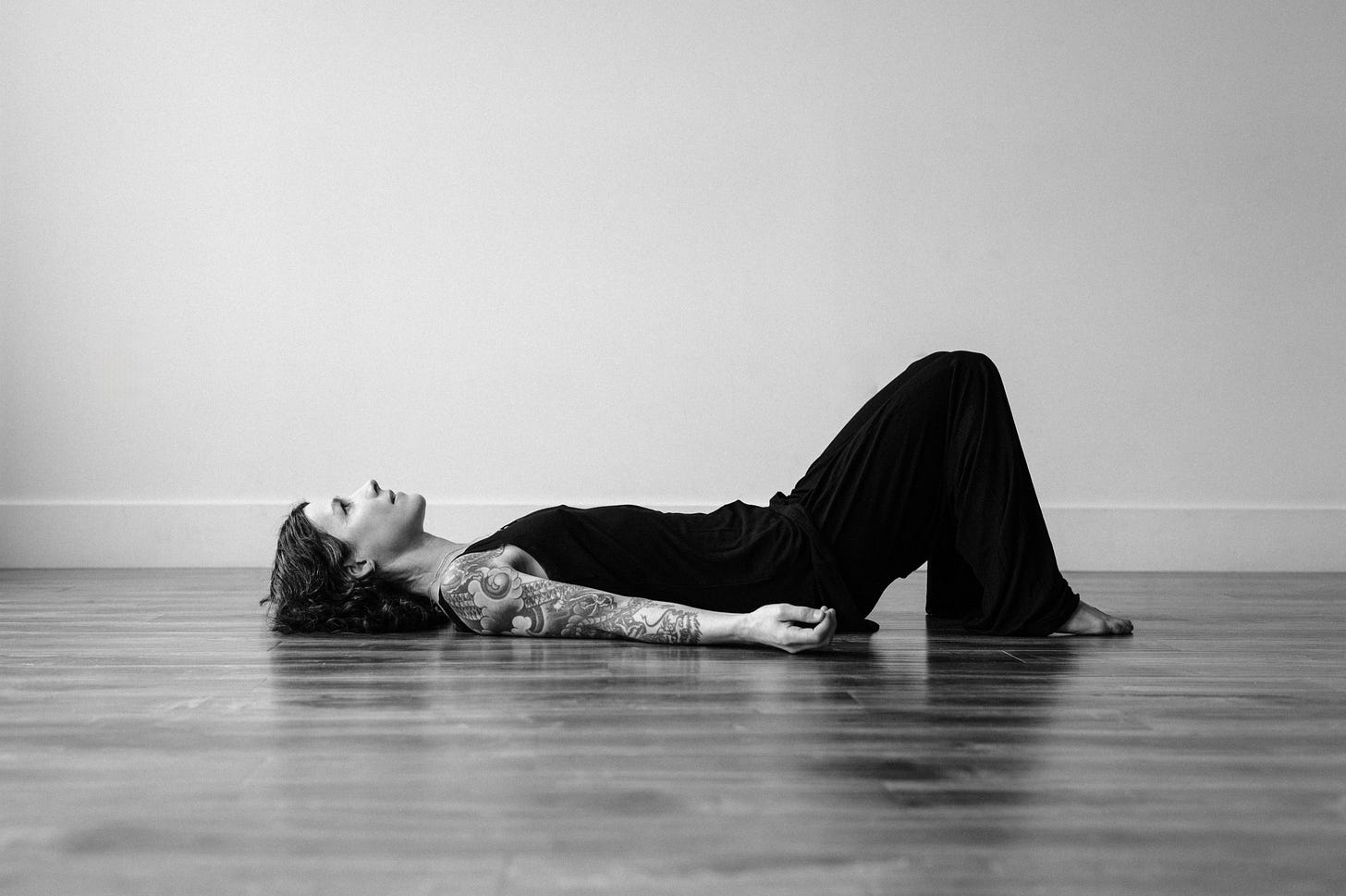 Author dressed in black lying on the floor, looking at the ceiling