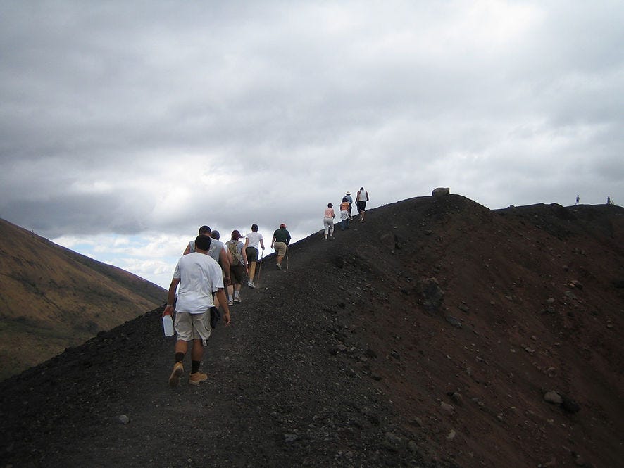 single file line of people hiking up volcano