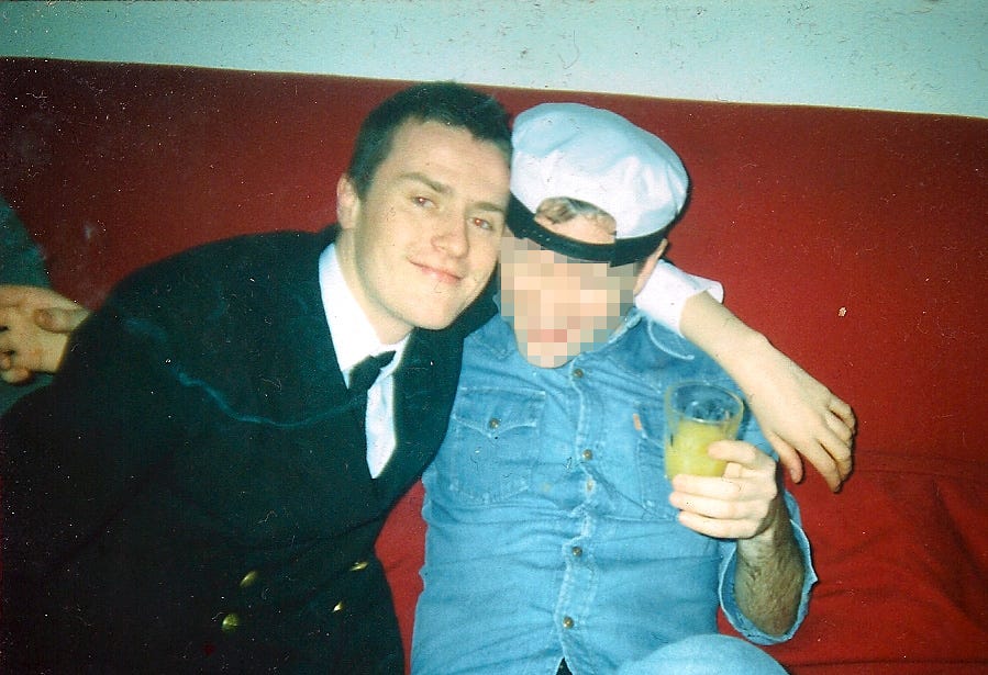 A younger me at a party in Edinburgh, dressed as a pilot, with a friend who is wearing my pilot hat
