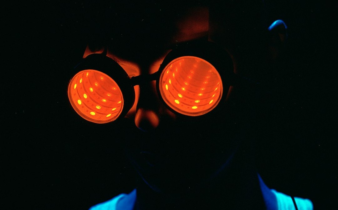 a man wearing a pair of red goggles in the dark a man wearing a pair of red goggles in the dark