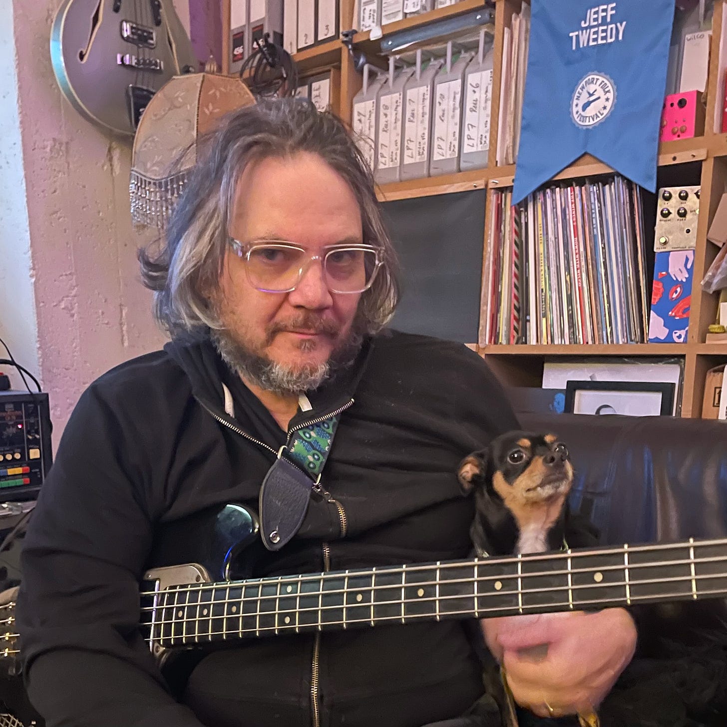 Jeff poses with Basil, Spencer and Casey’s chihuahua, while Jeff holds a bass guitar, on the couch in the Loft’s control room.
