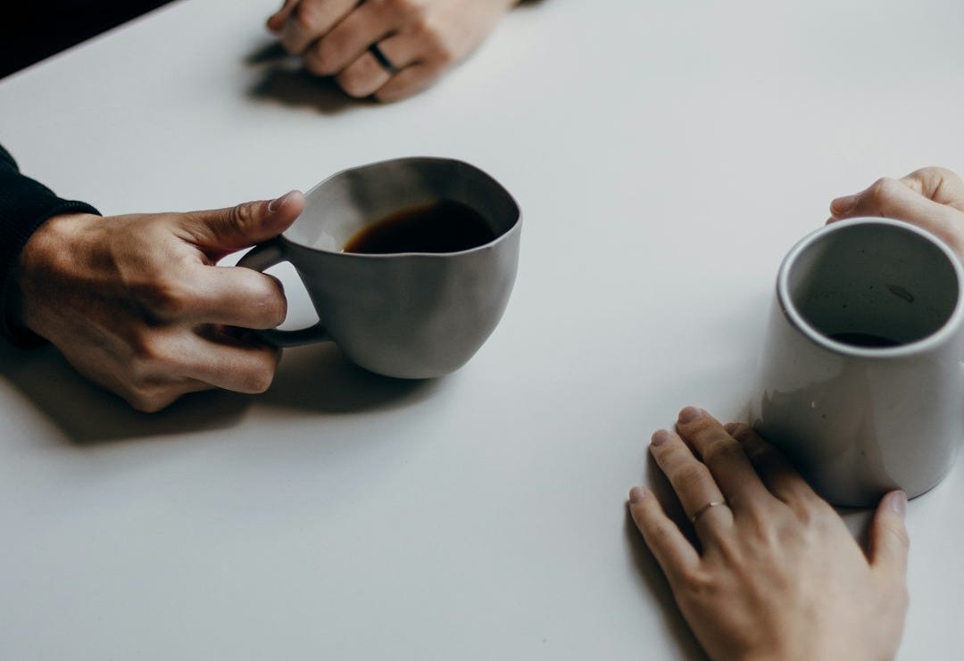 a couple of people sitting at a table with cups of coffee