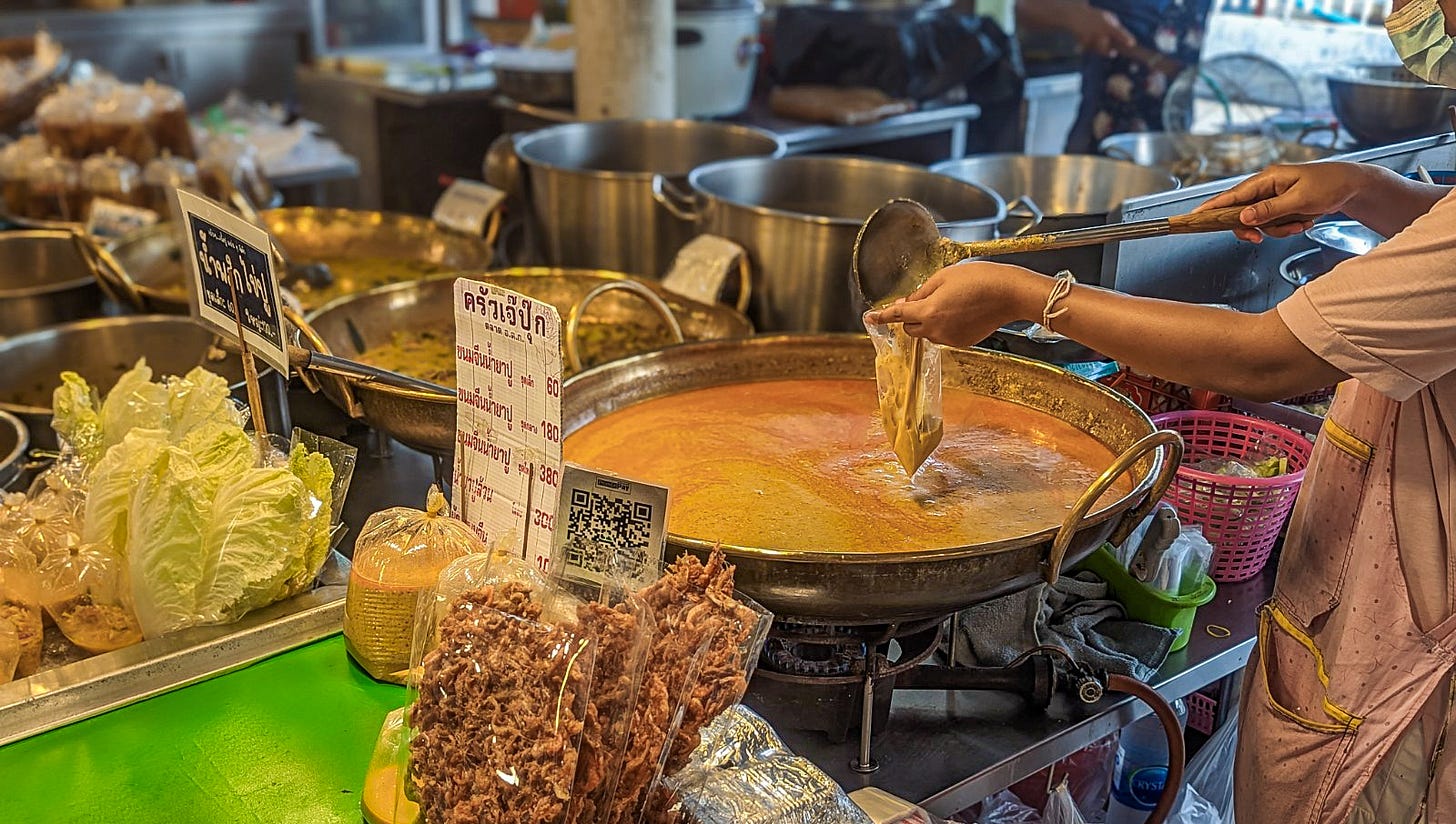 Woman ladling red curry into a plastic bag. 