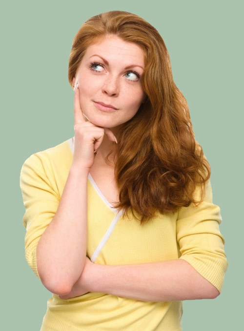 Woman with long red hair and yellow jumper in a "I wonder" pose