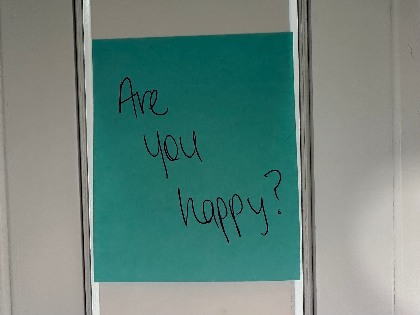 Blue post-it note that reads, "Are you happy?"
