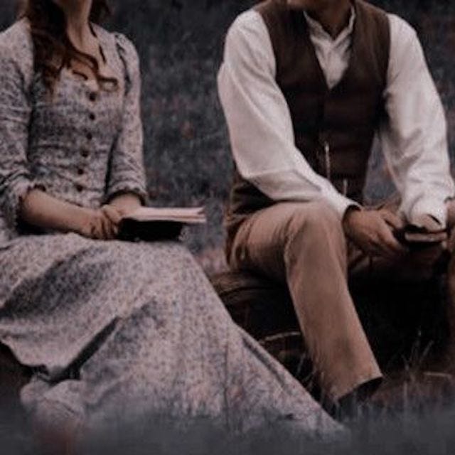 This may contain: the man and woman are sitting together on the grass with an open book in their hands