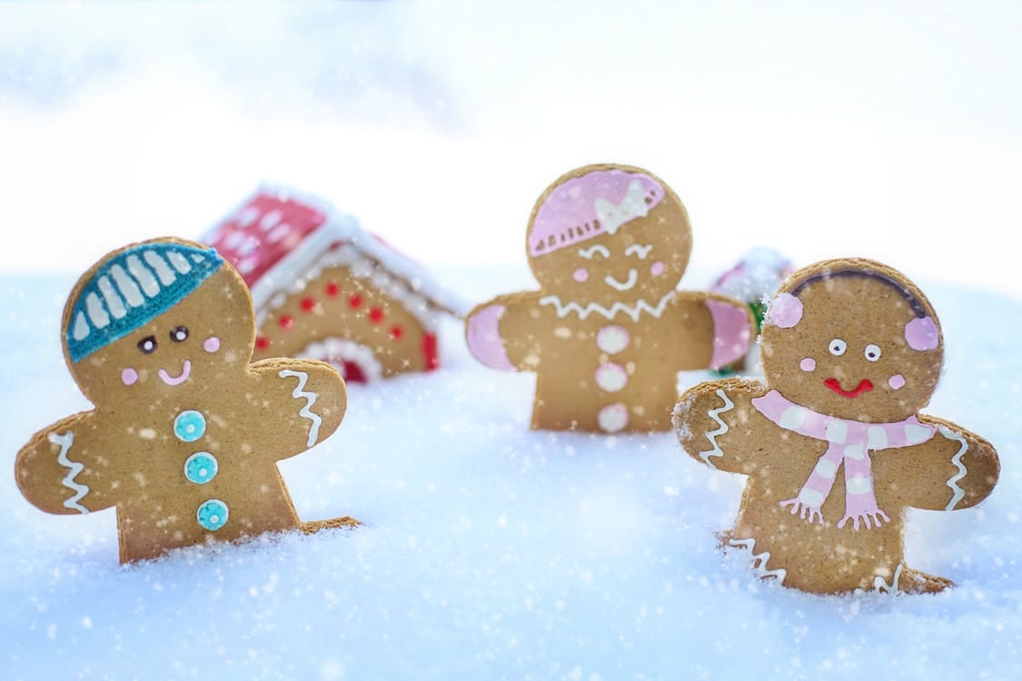 Free Three gingerbread figures in snow, celebrating a cheerful winter season. Stock Photo