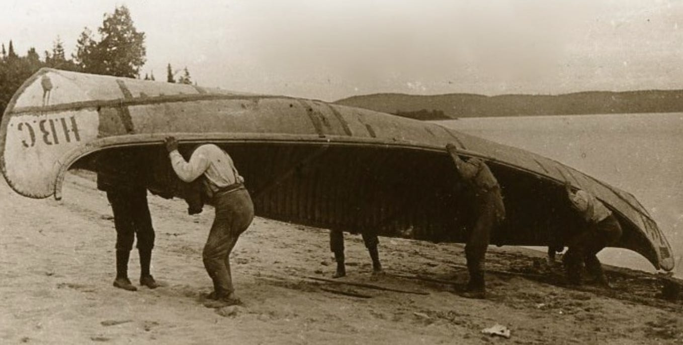 People lifting large canoe above their heads for portage