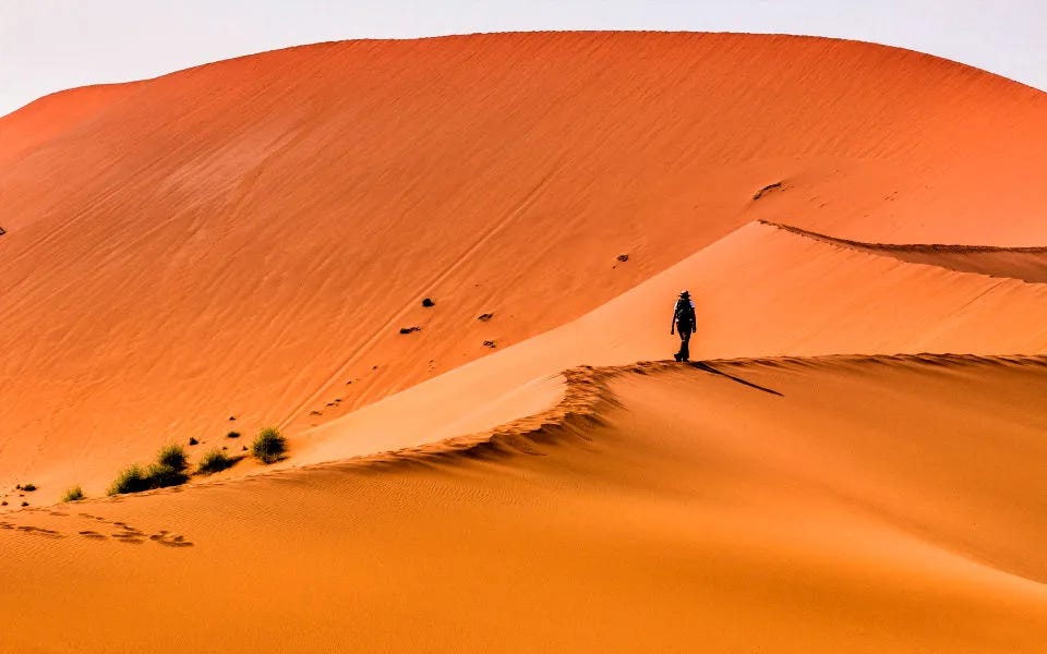 Une personne seule marchant dans les dunes du désert