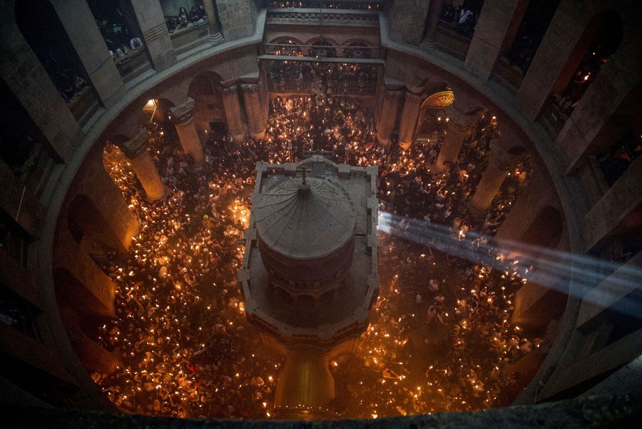 An elevated view of worshippers carrying candles around a shrine inside a church chamber.