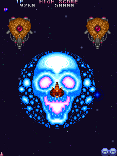 A screenshot of Truxton's giant skull bomb being used against the first mini-boss in stage 1 of the game. The bomb isn't screen-clearing, but it's large, and it explodes into a giant blue fire skull before flashing in place as more explosions to damage anything that comes into its range.