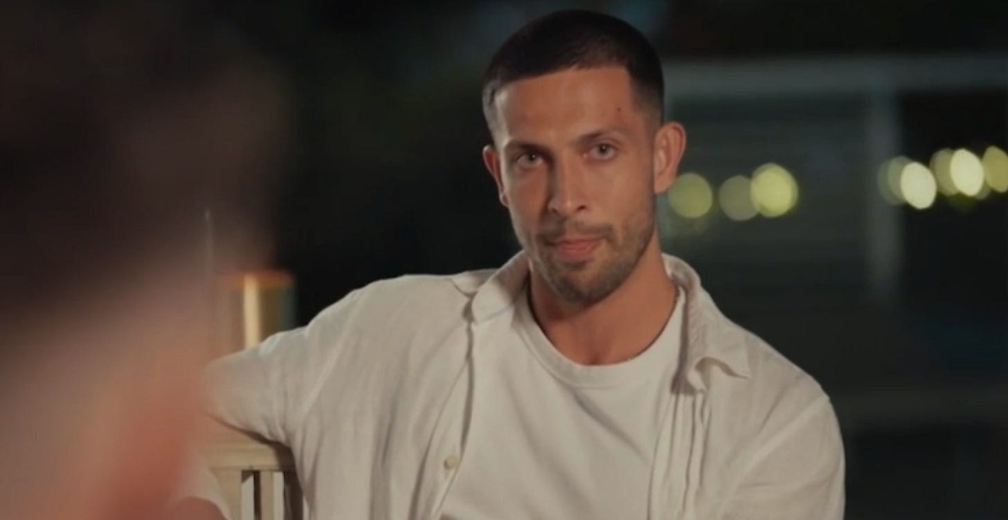 Teejay sits outdoors at night, wearing a white shirt and giving a subtle, serious look.