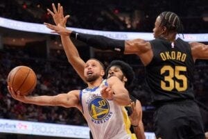 Golden State Warriors guard Stephen Curry goes to the basket in front of Cleveland Cavaliers center Jarrett Allen, rear, and forward Isaac Okoro in the first half of an NBA basketball game on Friday, Nov. 8, 2024, in Cleveland. (AP Photo/Sue Ogrocki)