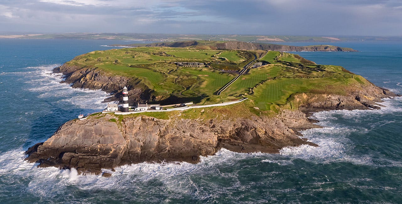 Aerial view of Old Head Golf Links in Ireland, showing a dramatic peninsula with emerald green fairways perched atop 300-foot cliffs. A distinctive black and white lighthouse stands at the point, surrounded by crashing Atlantic waves against rugged coastline. Aerial view of Old Head Golf Links in Ireland, showing a dramatic peninsula with emerald green fairways perched atop 300-foot cliffs. A distinctive black and white lighthouse stands at the point, surrounded by crashing Atlantic waves against rugged coastline.