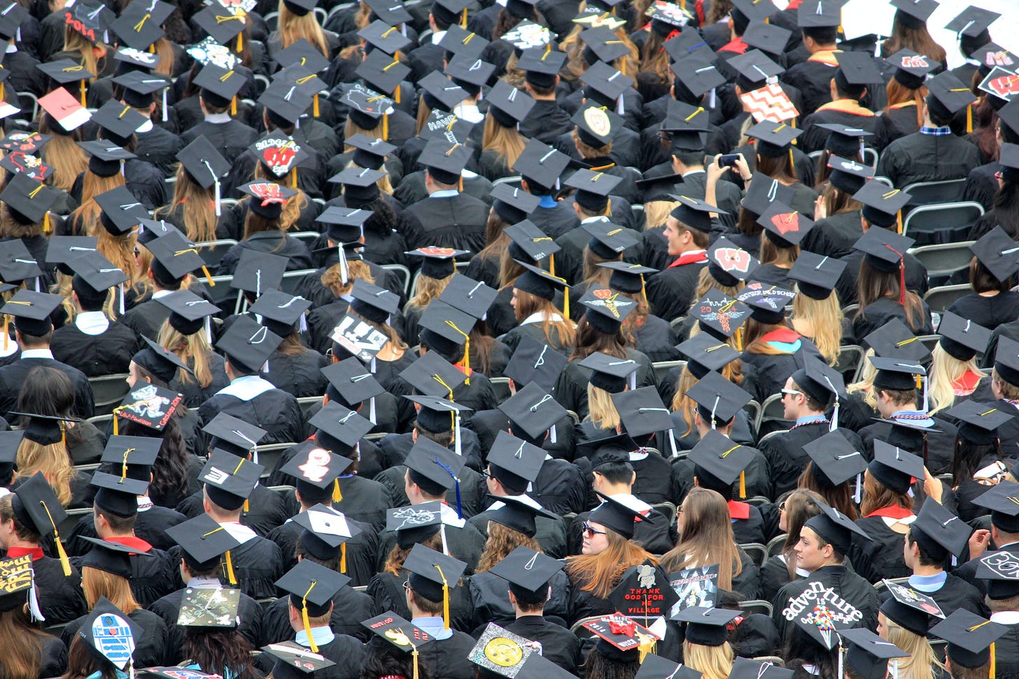A crowd of graduates in cap and gown. The caps are black. 