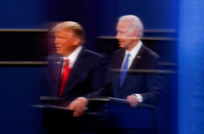 President Donald Trump and Democratic presidential nominee Joe Biden are reflected in the plexiglass protecting a TV camera operator from COVID-19 during a presidential debate in Nashville, Tenn., in 2020.
