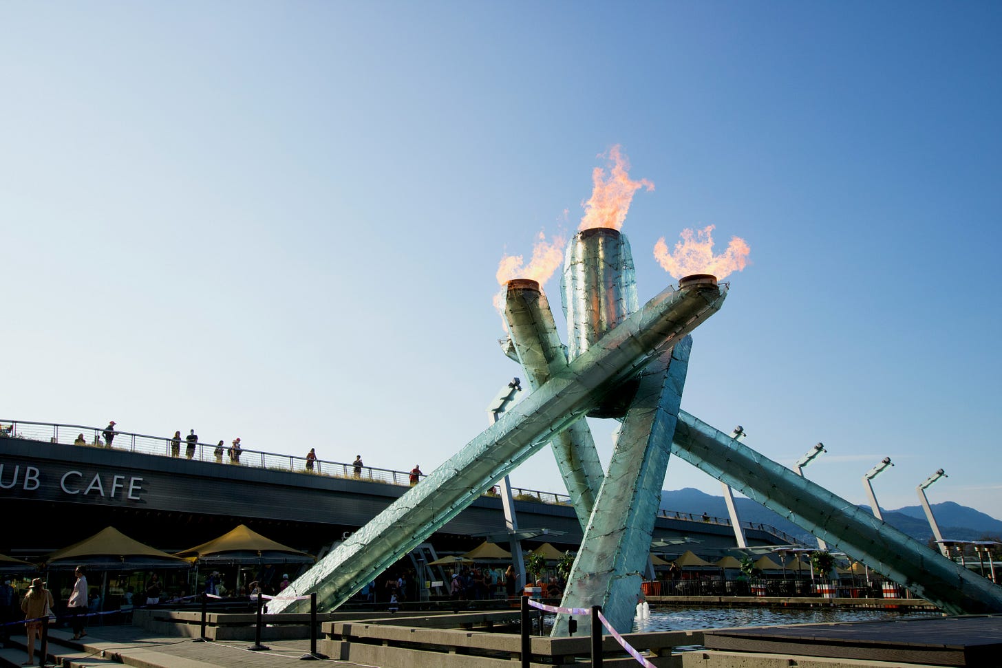 The Vancouver 2010 Olympic cauldron. In the foreground, a cauldron made of four metal cylinders leaning on each other. There are three flames in view at the top.