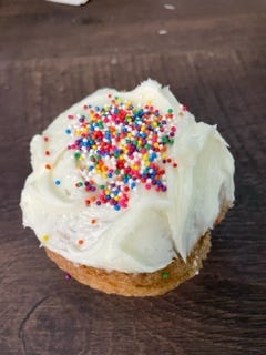 A spice cake flavored cupcake with cream cheese frosting and colorful candied decorations.