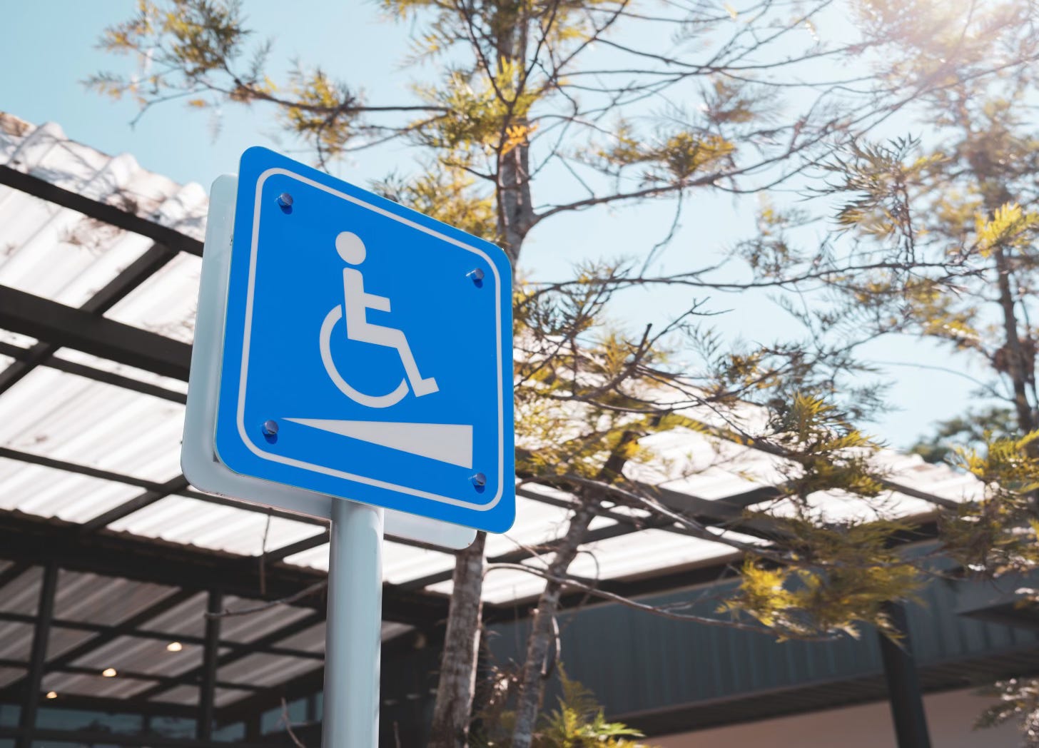 Outdoor sign with wheelchair symbol marking wheelchair ramp