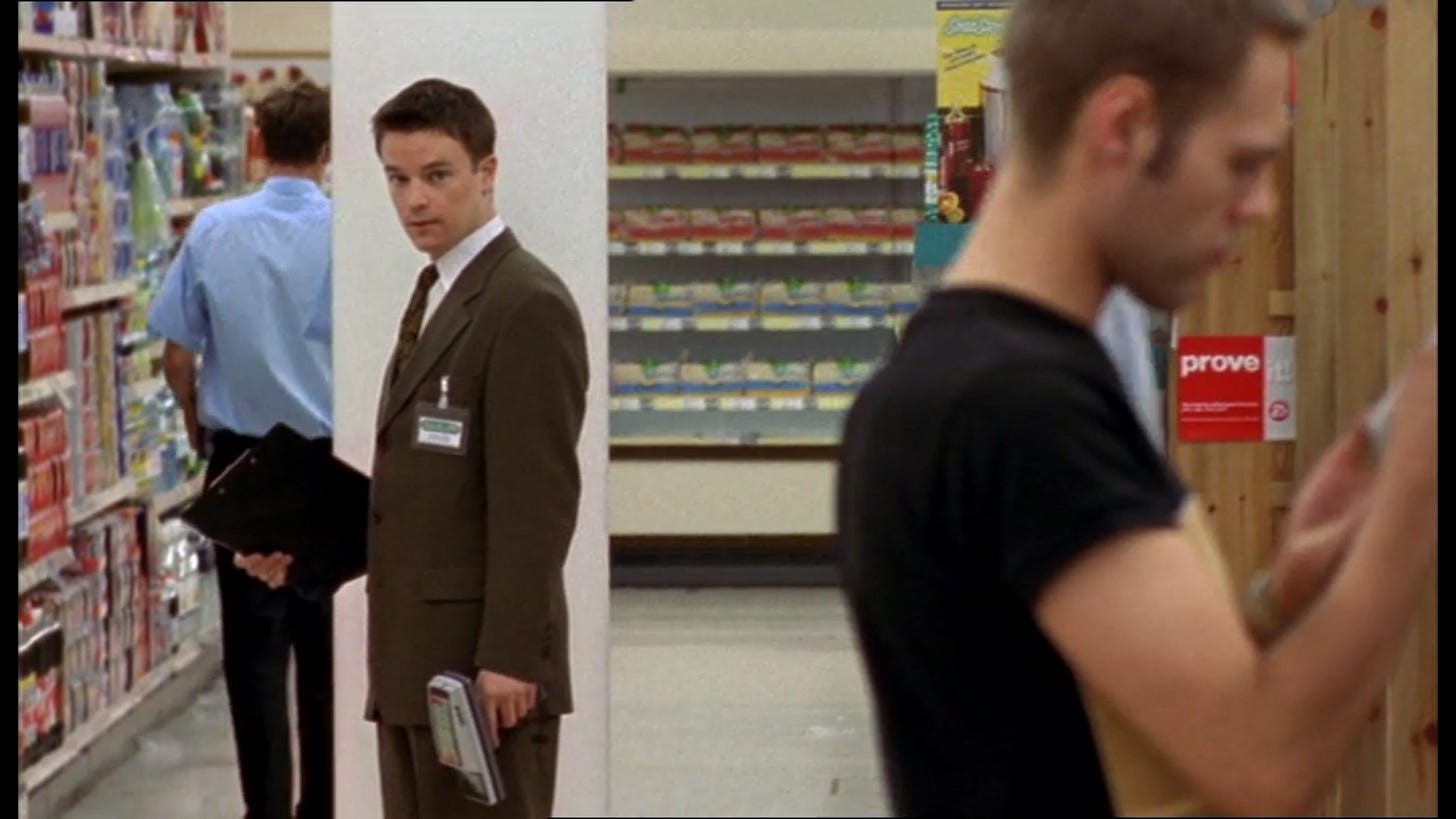 Craig Kelly as Vince Tyler, standing with a clipboard in a supermarket checking out an attractive man.