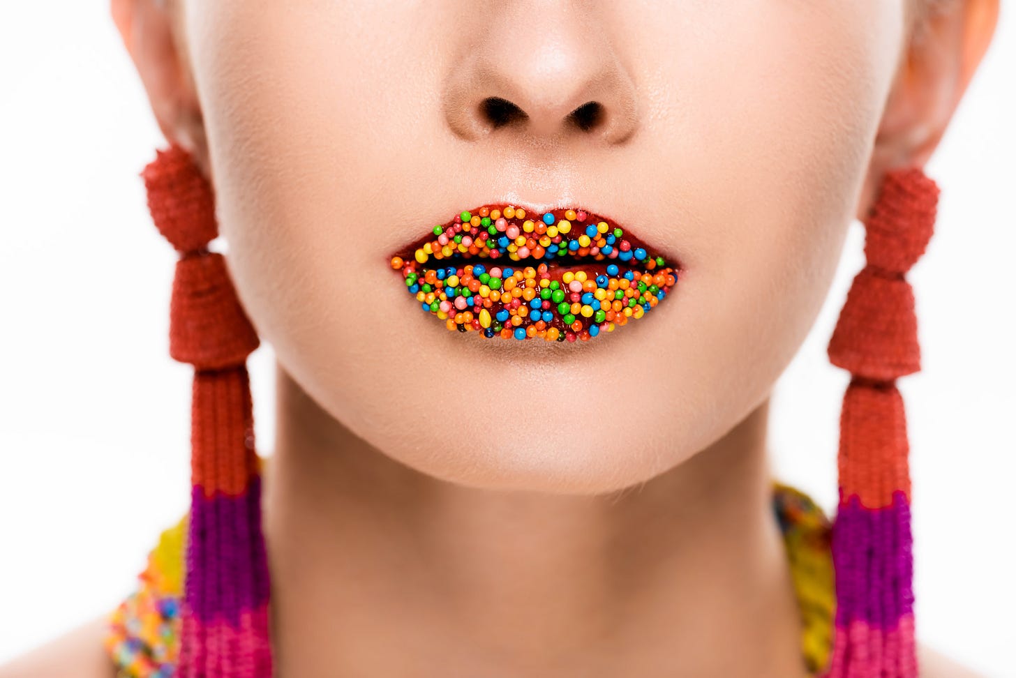 Utterly stupid looking model waering earrings that look like socks and lipstick on her lips covered in multi colored tiny ball-like candies found on cupcakes or donuts