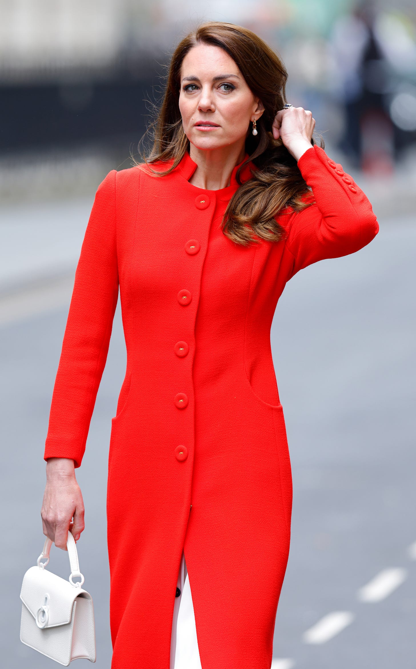 Kate Middleton in a red coat touching her hair