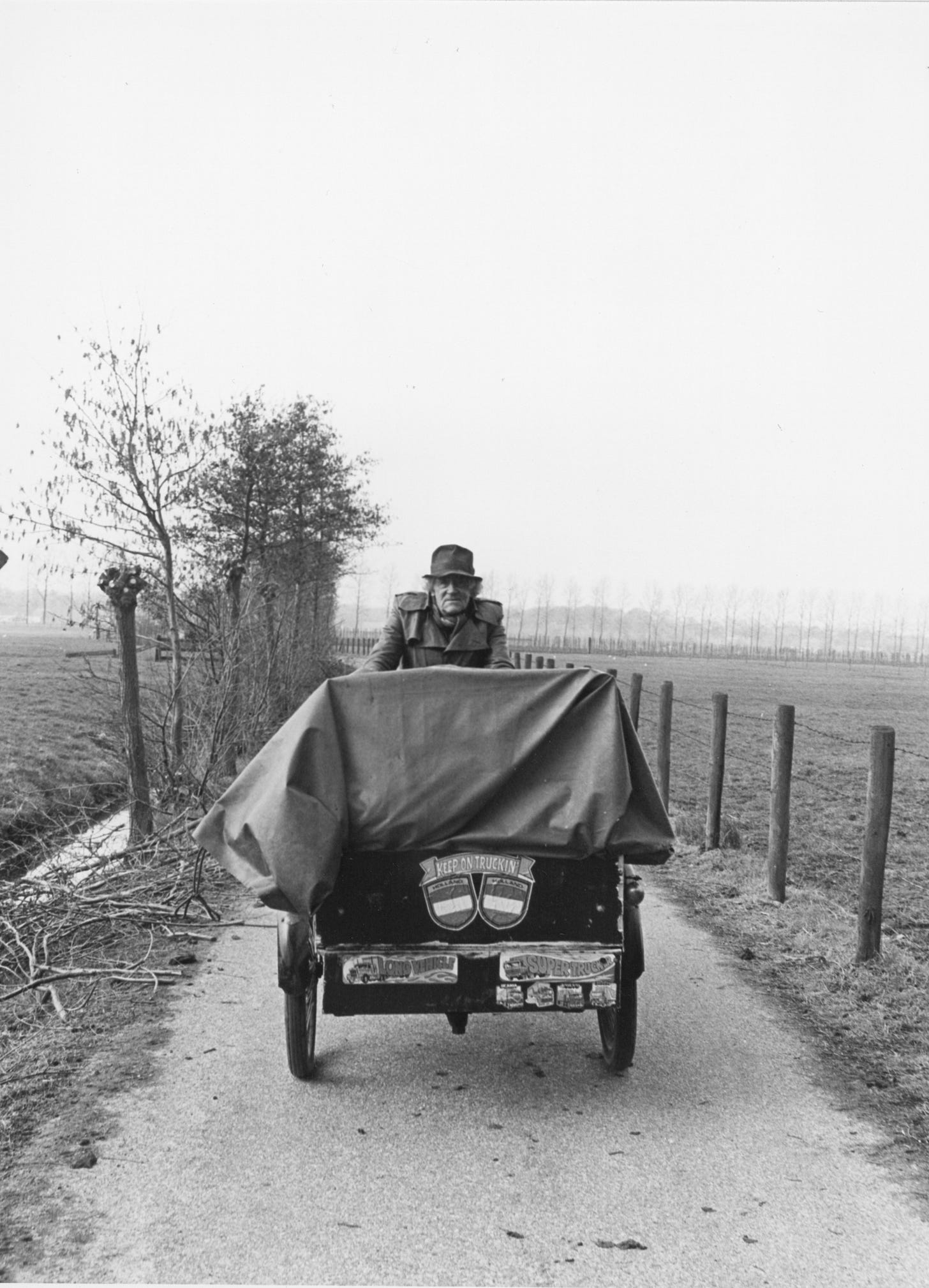 A man cycles a cargobike along a narrow country road