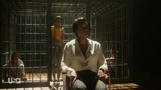 a woman seated in a cage; still from the Purge