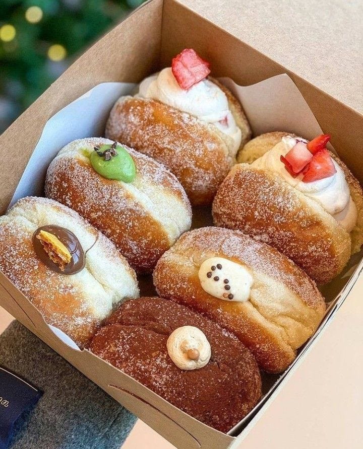 This may contain: a box filled with donuts covered in frosting