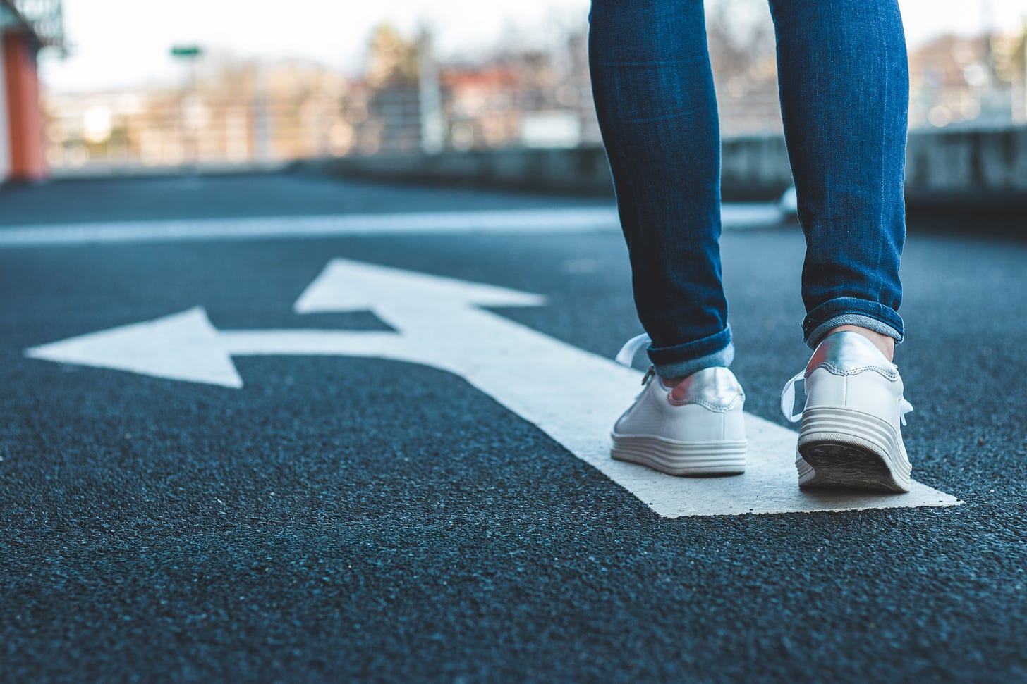 A woman walks along an arrow painted on the ground. Concept: choosing a direction.