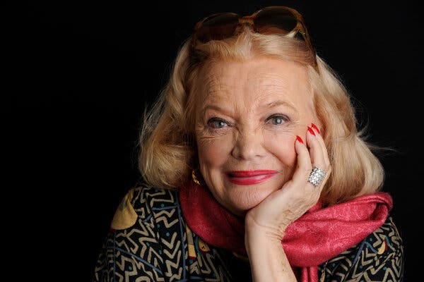 Gena Rowlands holds her face with her right hand and has sunglasses perched atop her head.