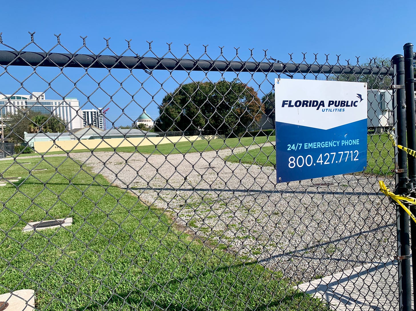 Fenced lot with West Palm Beach City Hall in the distant background.