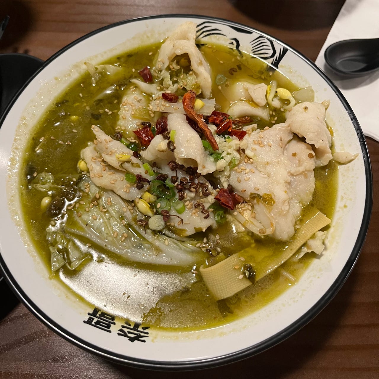 A greenish gold stew with chunks of white fish, cabbage, and peppercorns.