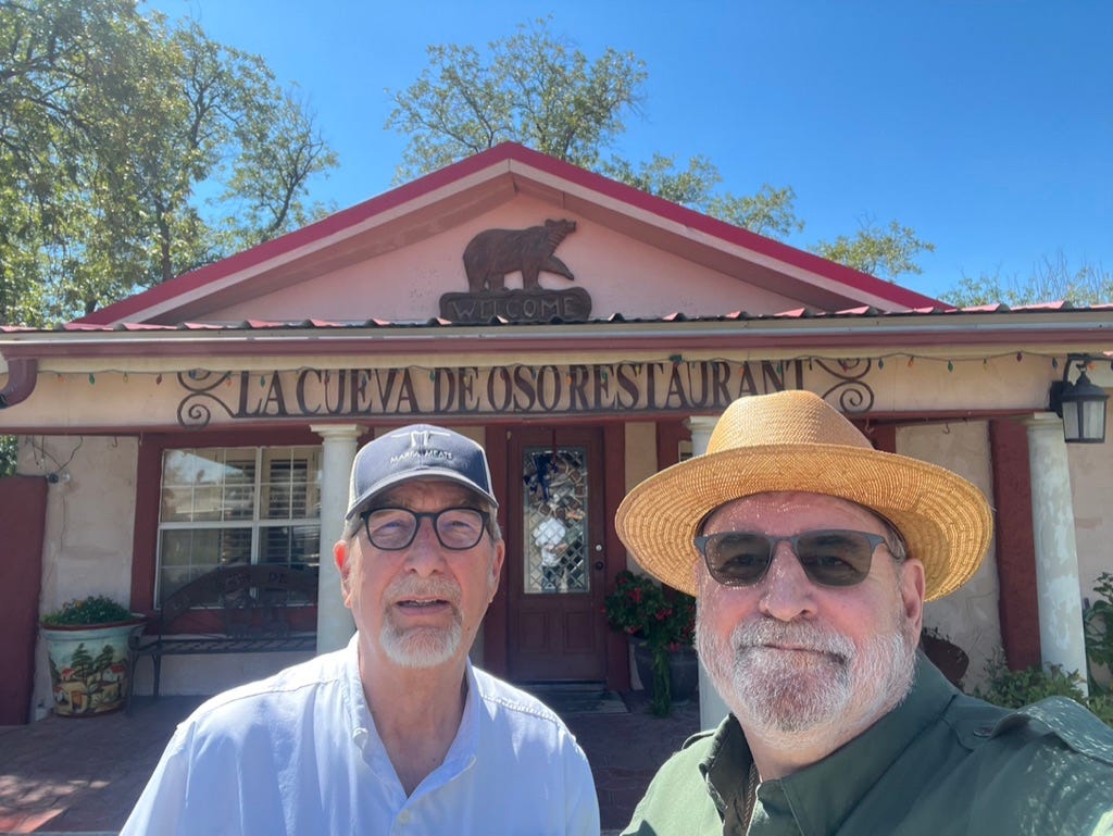 Two men standing in front of a restaurant

Description automatically generated