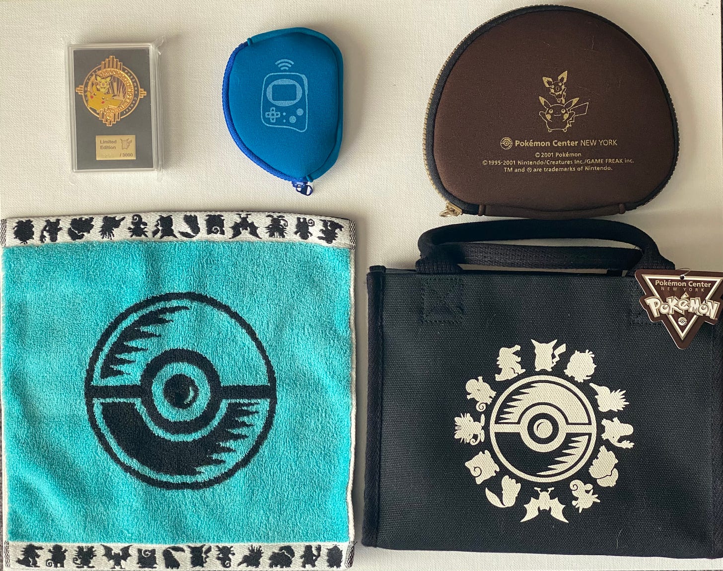 Tatton shared some of the items he still owns from his visit to the Pokémon Center New York store, including a Grand Opening pin badge (0293/3000), Game Boy Advance and Pokémon Mini protective cases, a Poké Ball towel, and a bag which still has its original tag