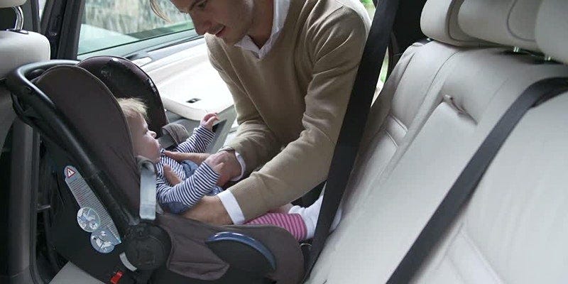 A man putting his child into a car seat