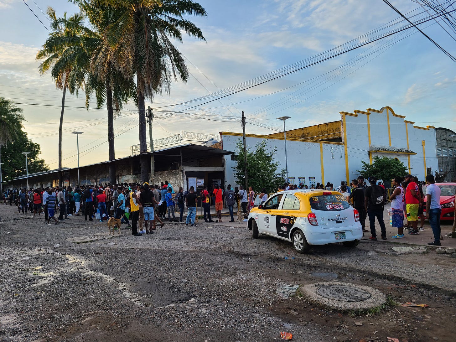 A group of asylum seekers, mostly from Haiti, stand in a street next to a building A group of asylum seekers, mostly from Haiti, stand in a street next to a building