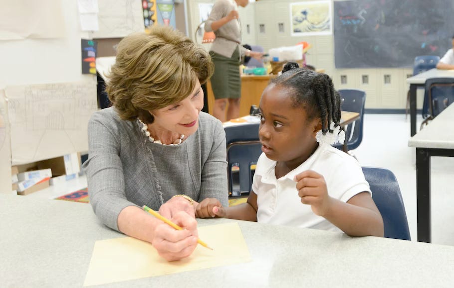 Former First Lady Laura Bush sits with a student in a classroom. Last week, the Laura Bush Foundation for America’s Libraries opened grant applications for schools in the United States that need to improve their libraries. (Photo: George W. Bush Presidential Center)