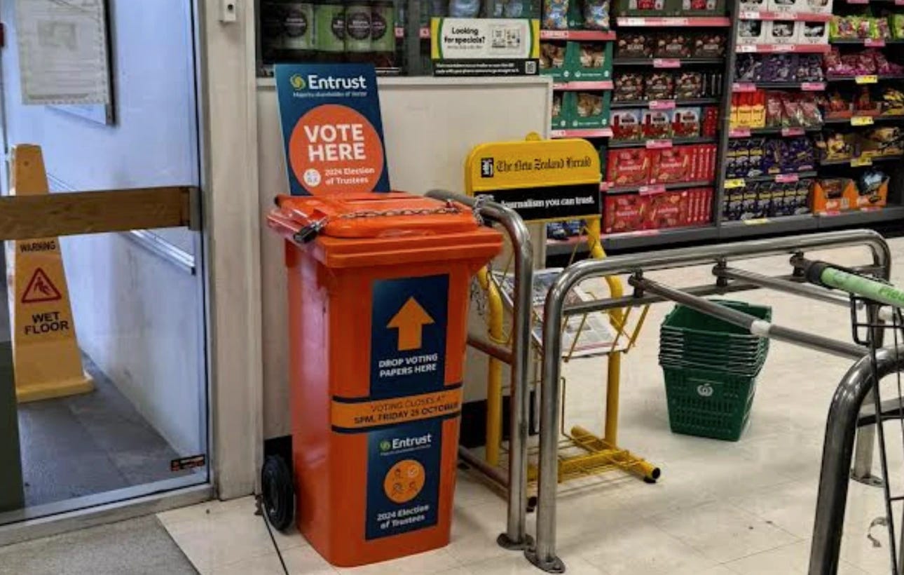 Photo of a bright orange wheelie bin at a supermarket with a sign saying "Entrust. Vote here"