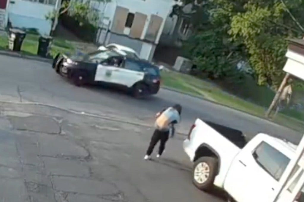 A Syracuse PD patrol car drives within feet of Jhon Moises Chacaguasay-Ilbis carrying a limp body. 