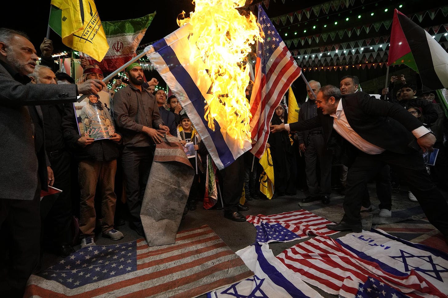 Iranian protesters in Tehran burn U.S. and Israeli flags.