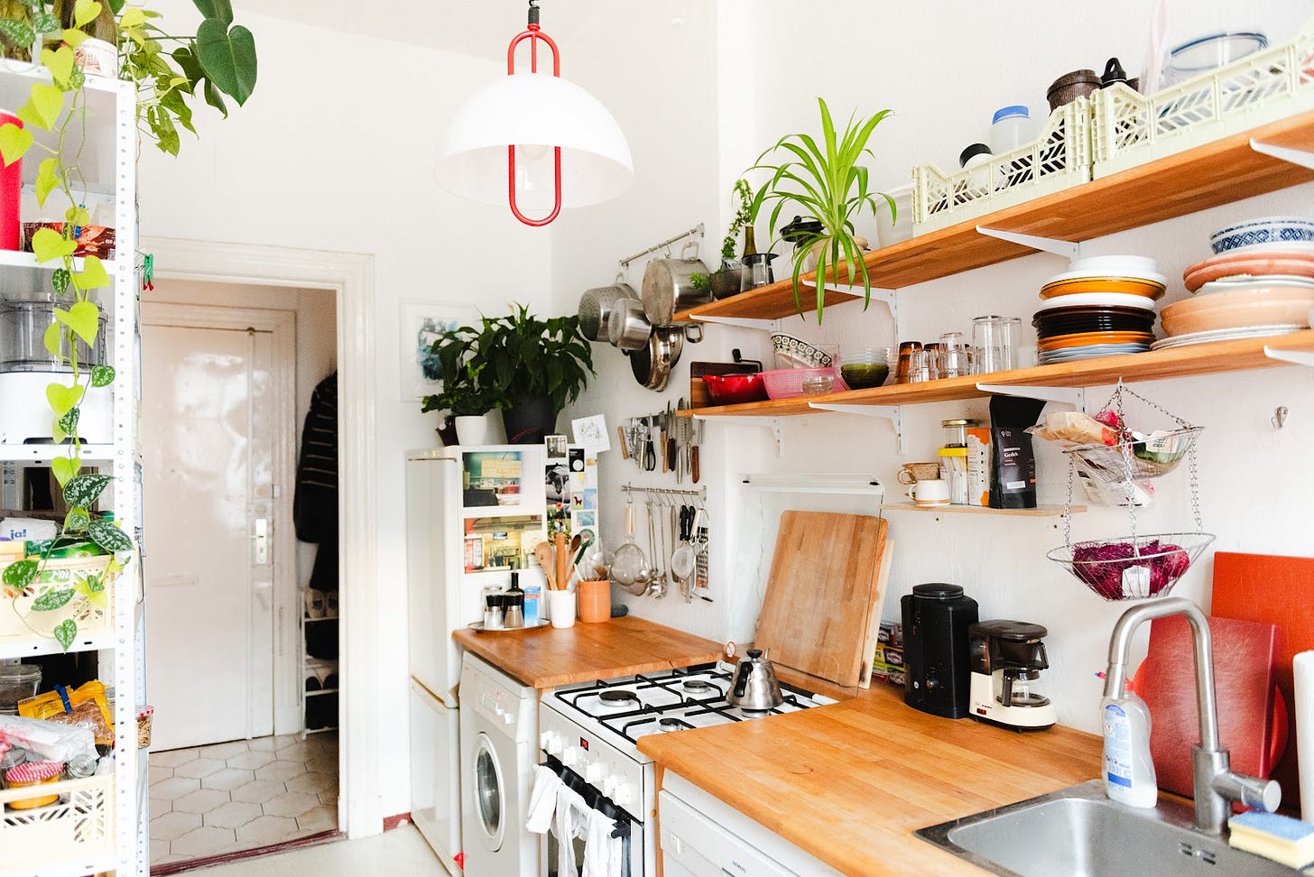 Kitchen with open wooden shelving and white walls.