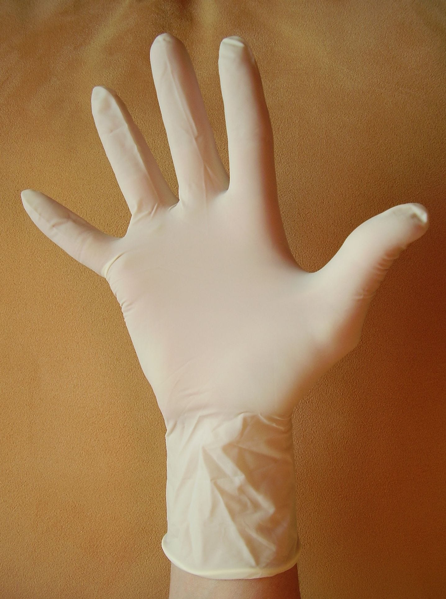 Splayed hand modeling a white disposable glove