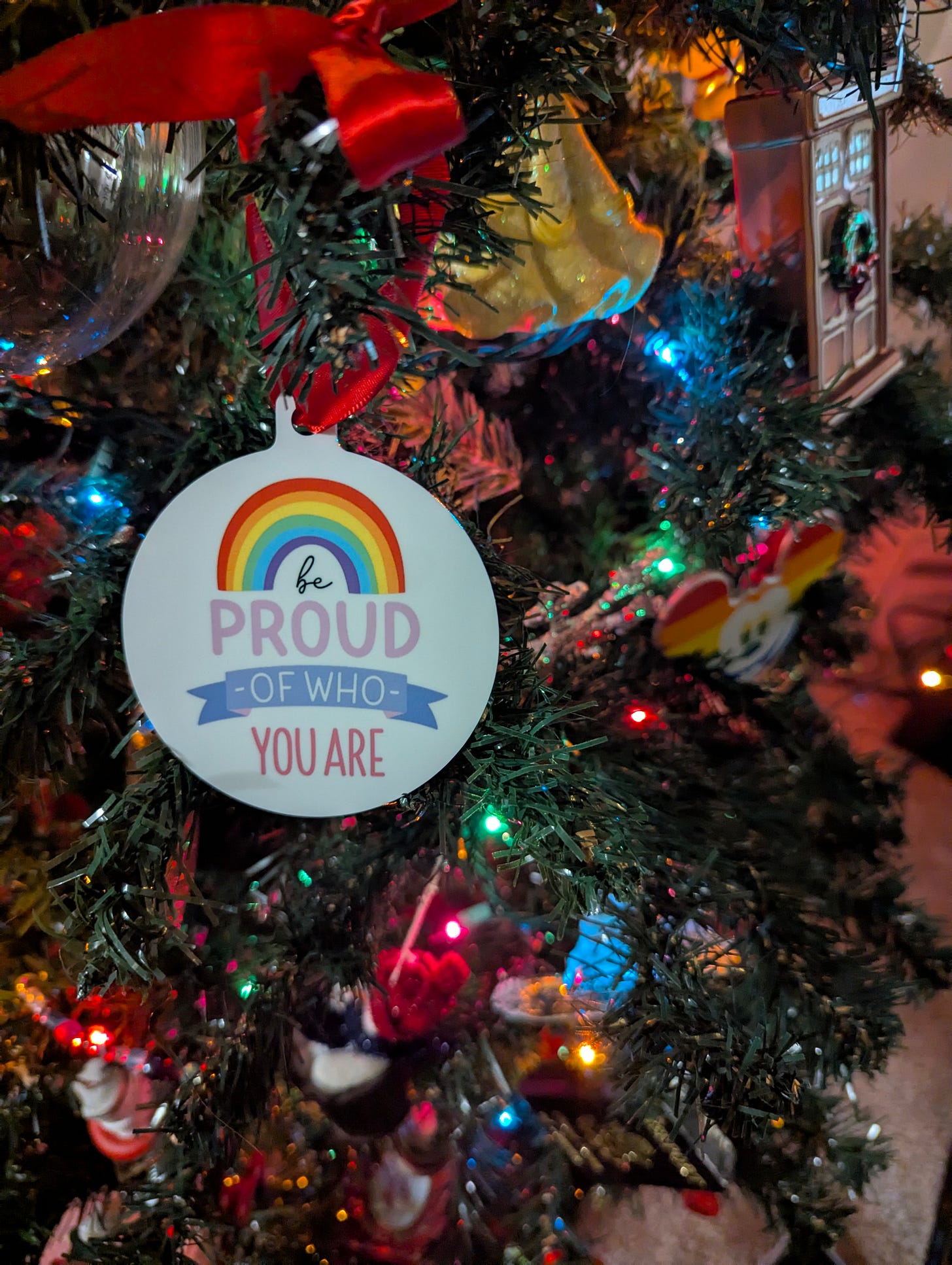 Ornament on a Christmas tree that says Be Proud of Who You Are
