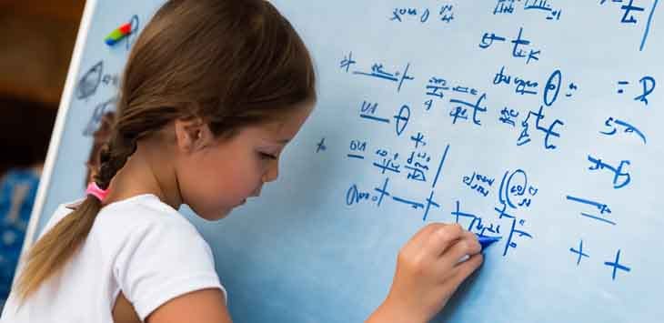 Photo of a child writing imaginary equations on a whiteboard.