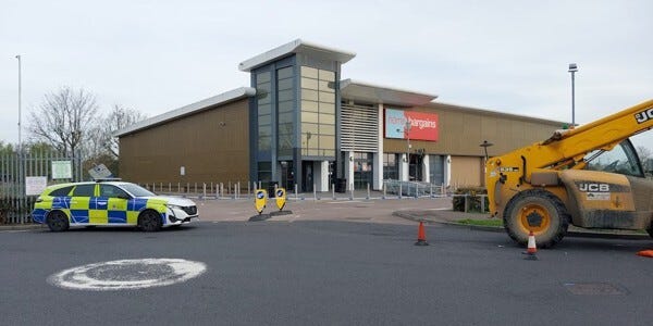 Home Bargains building with a JCB digger and police car in the foreground