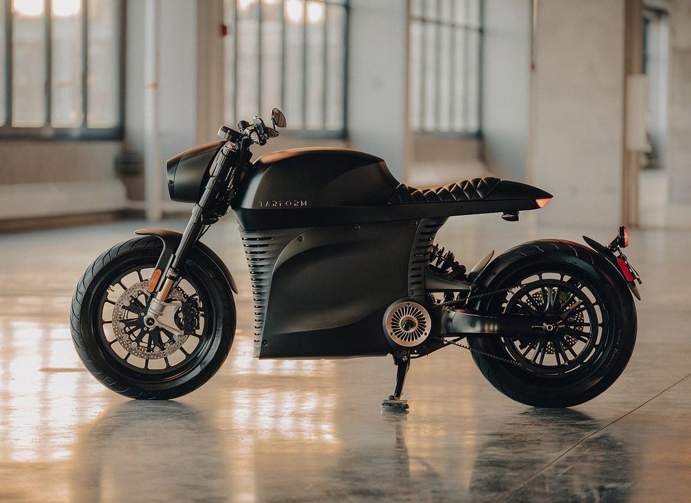 A Tarform Luna electric motorcycle on full display within a building. 