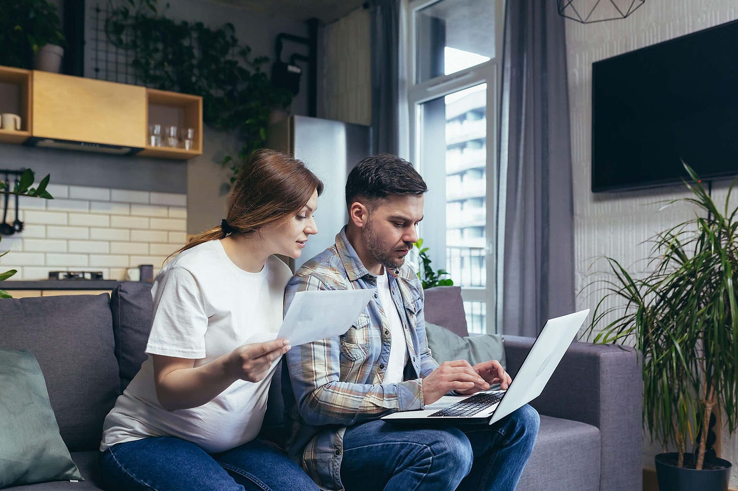 Pregnant couple looking at bills and finances on a laptop