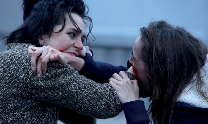 Two young white women with dark hair biting each other's arms